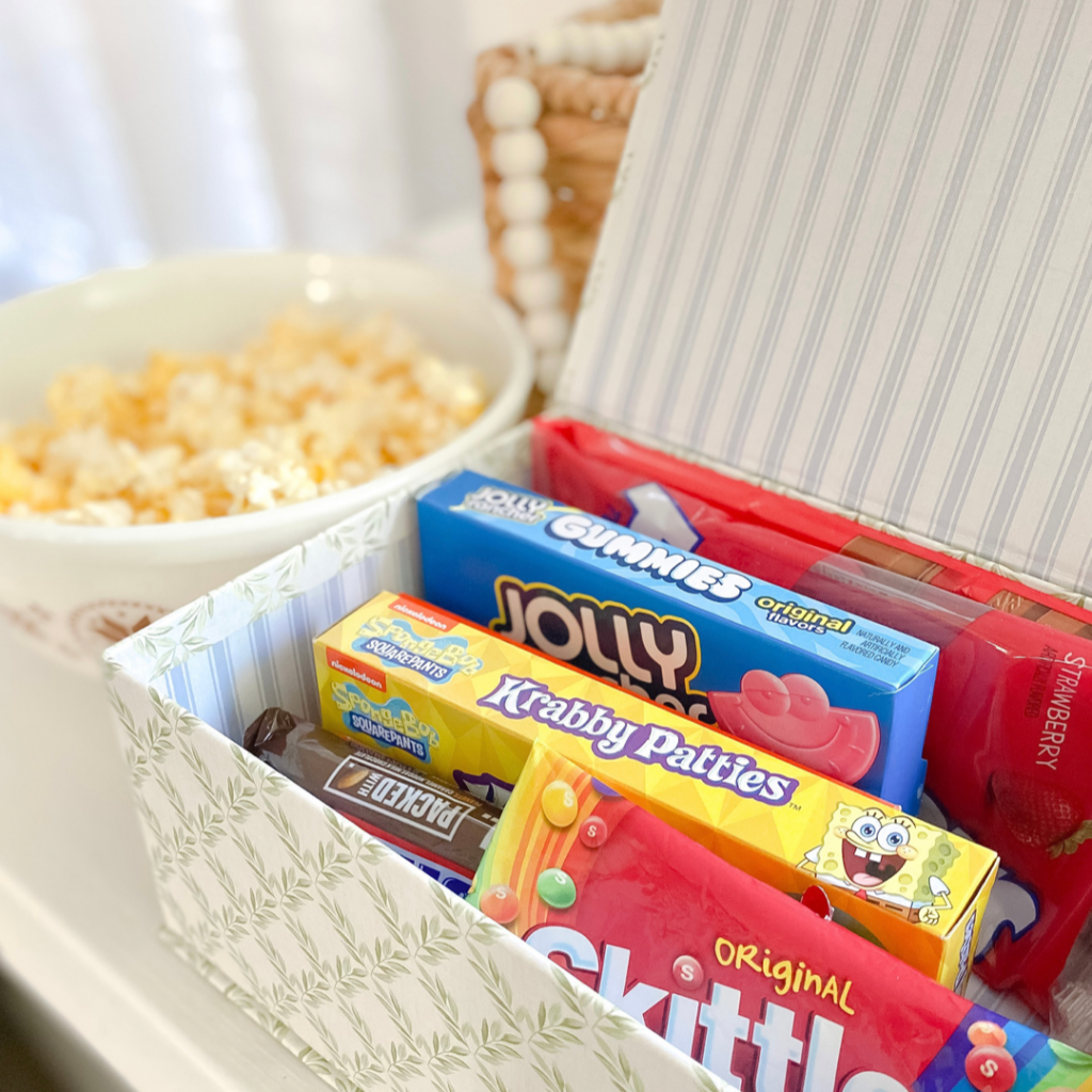 Popcorn in bowl beside basket of candies