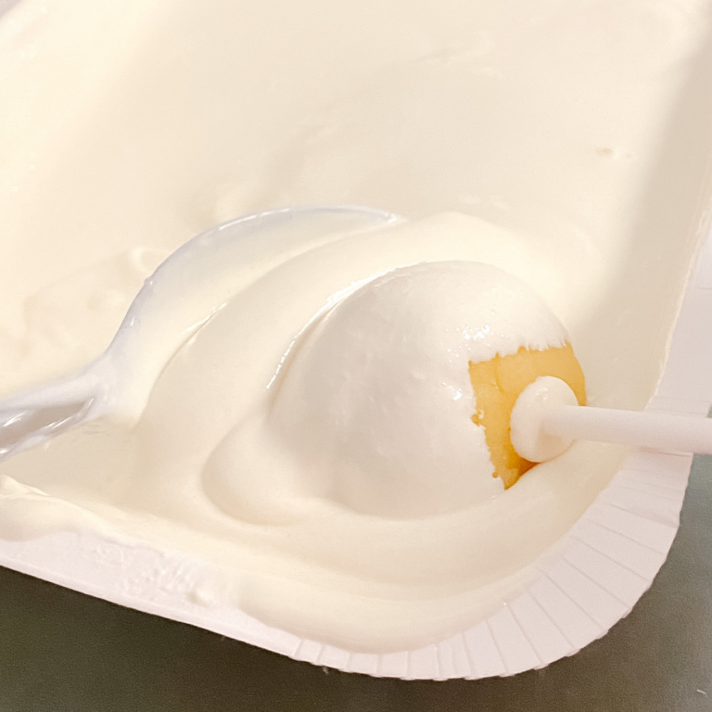 Cake pops being dipped into white chocolate.