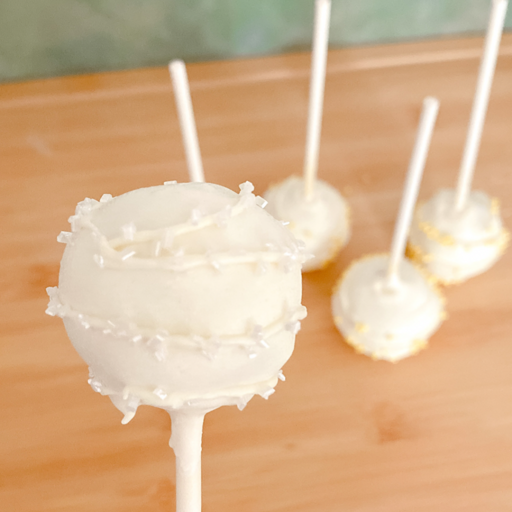 Decorated cake pop with coated in white chocolate and clear sprinkles.